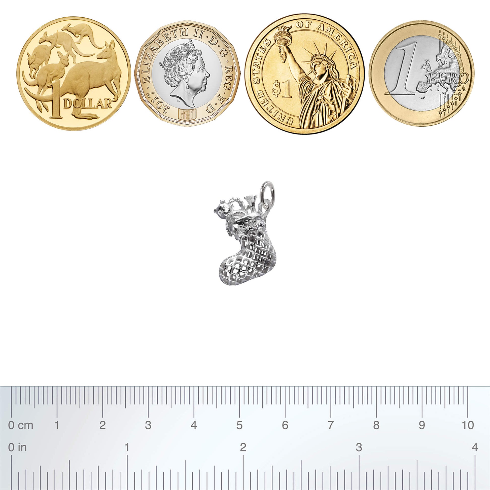silver Christmas stocking charm with coins and ruler for scale on white background