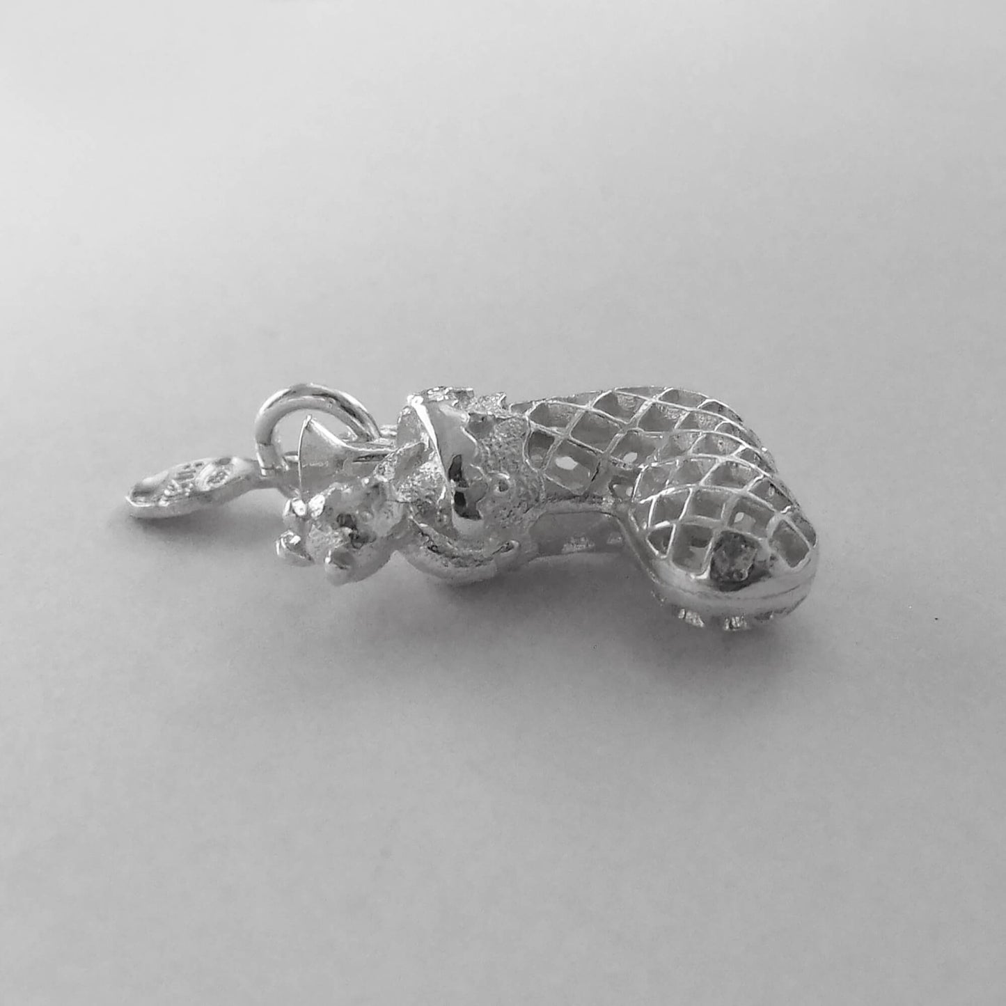 side view of silver Christmas stocking charm on grey background