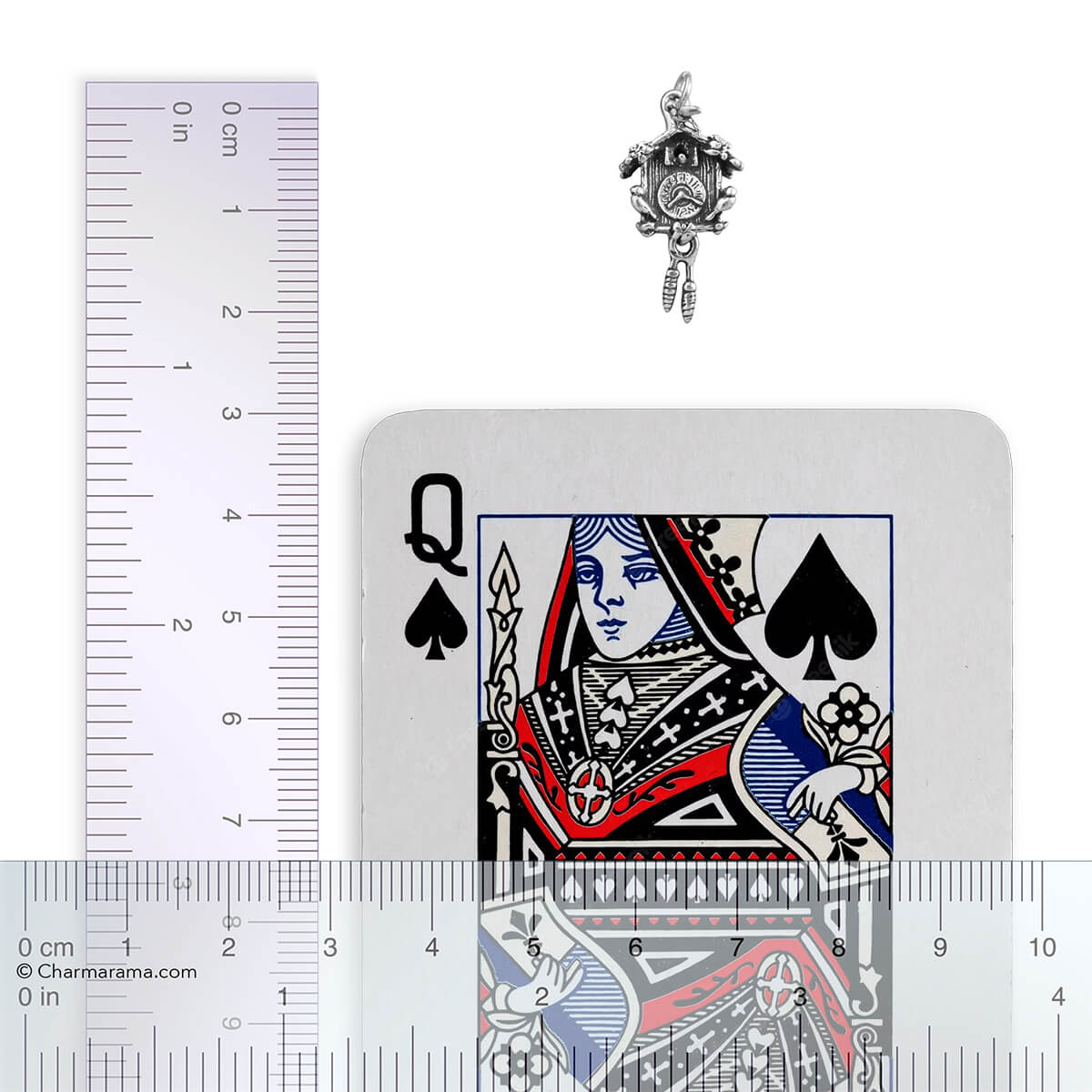 Silver cuckoo clock pendant next to a playing card with a ruler for scale.