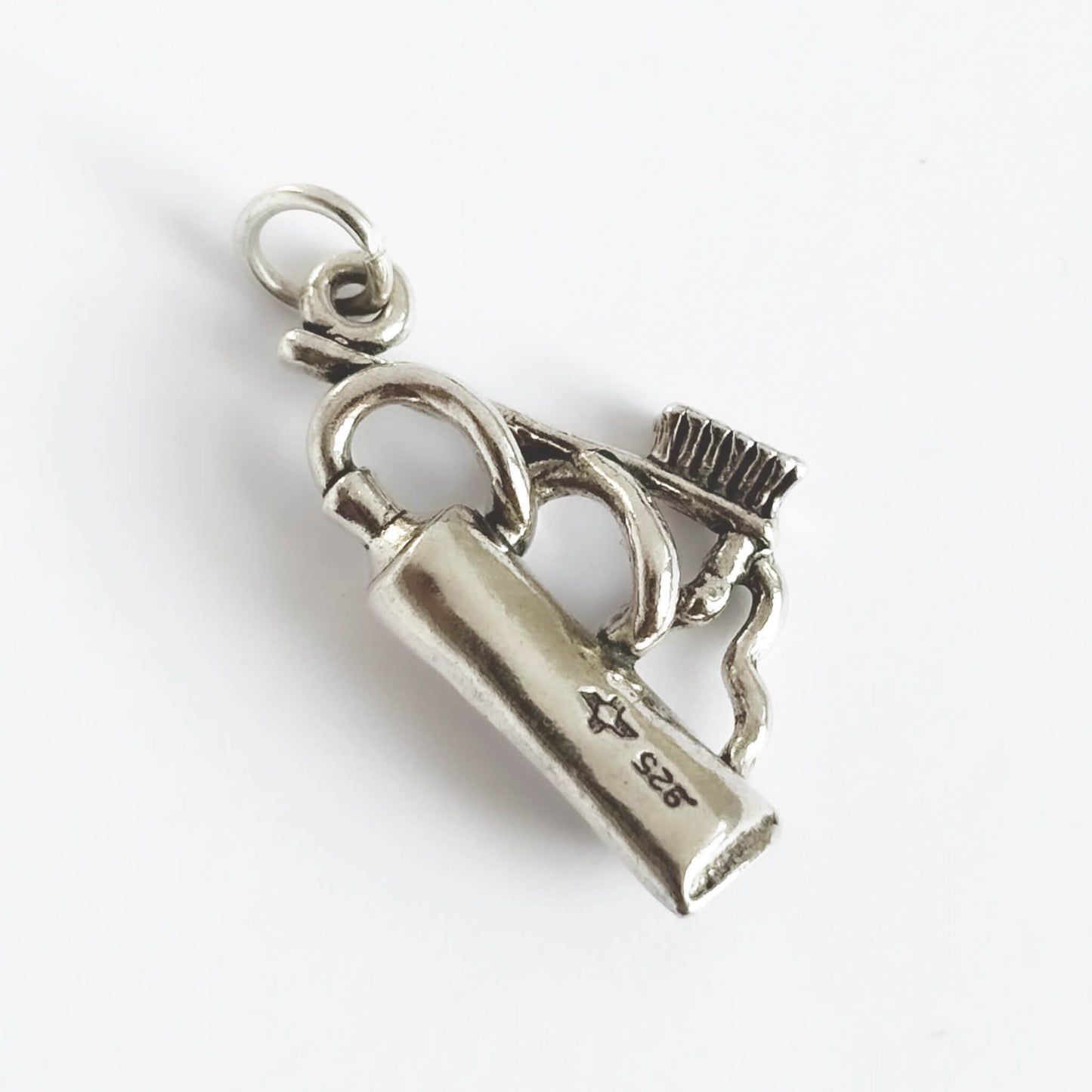 Silver toothpaste and toothbrush charm on white background