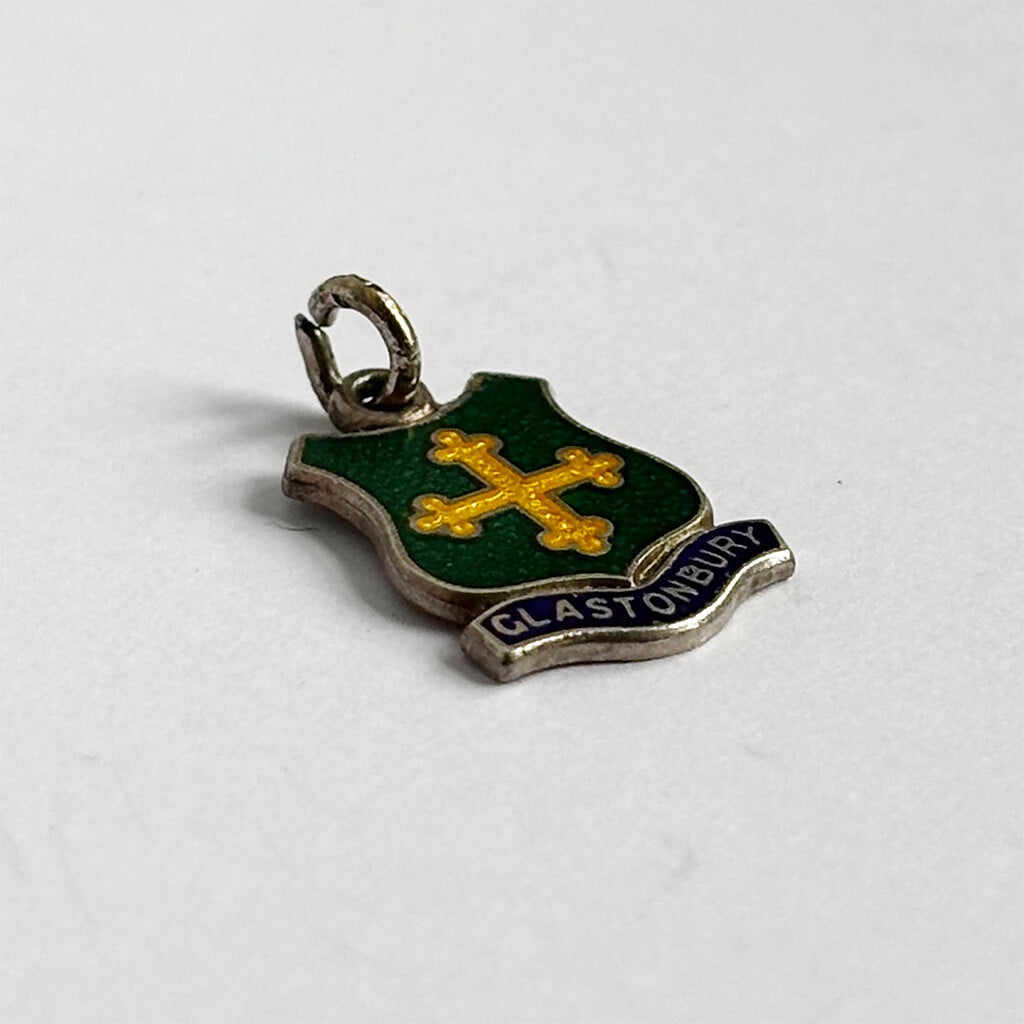 vintage silver green and yellow enamel emblem with 'Glastonbury' text on a white background