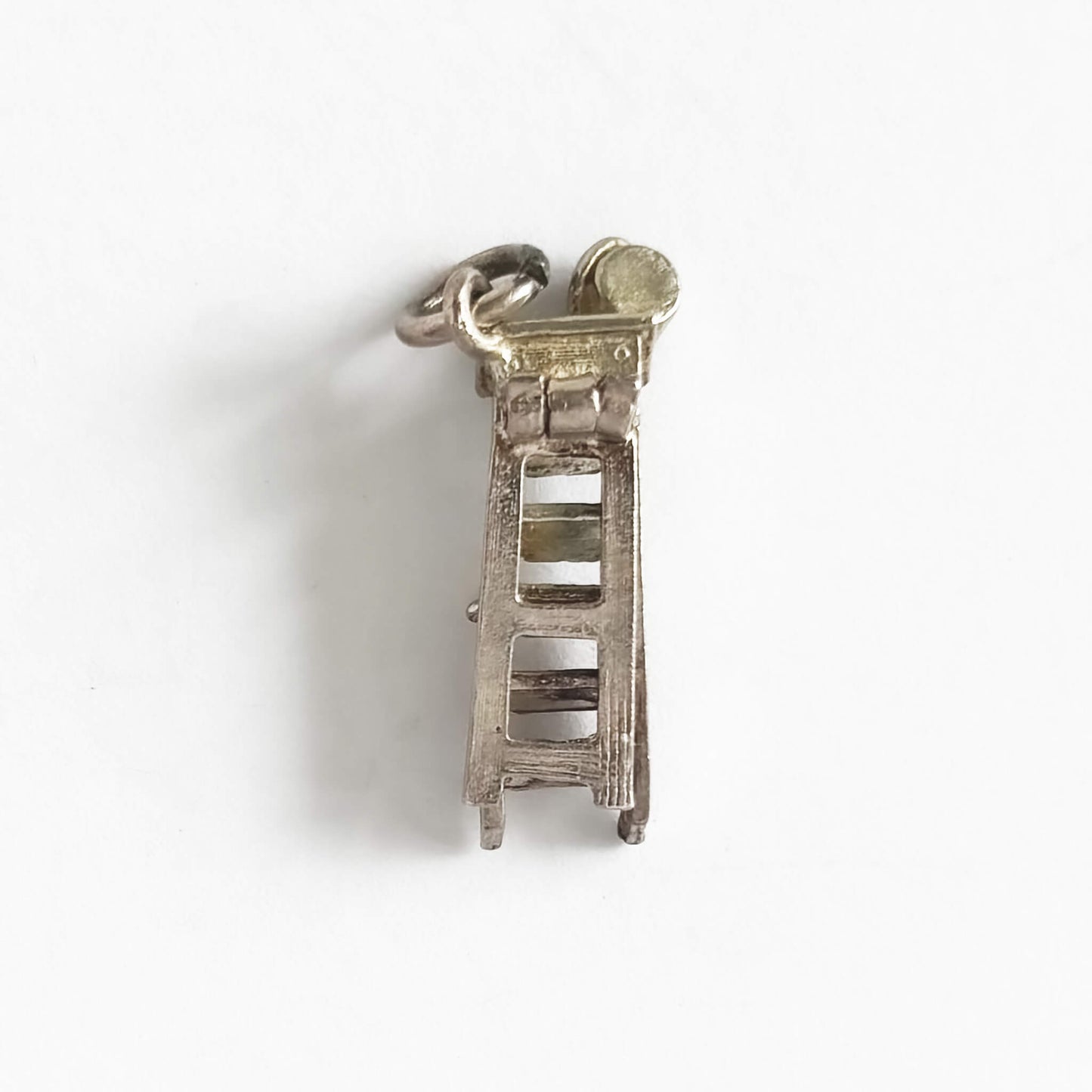 Silver ladder charm on a white background