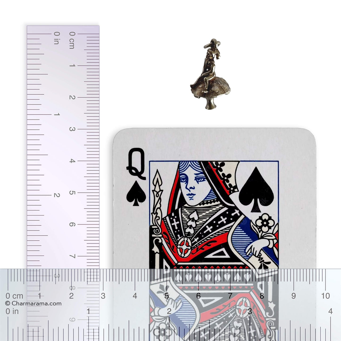 Silver leprechaun on toadstool charm with playing card and ruler for scale on a white background