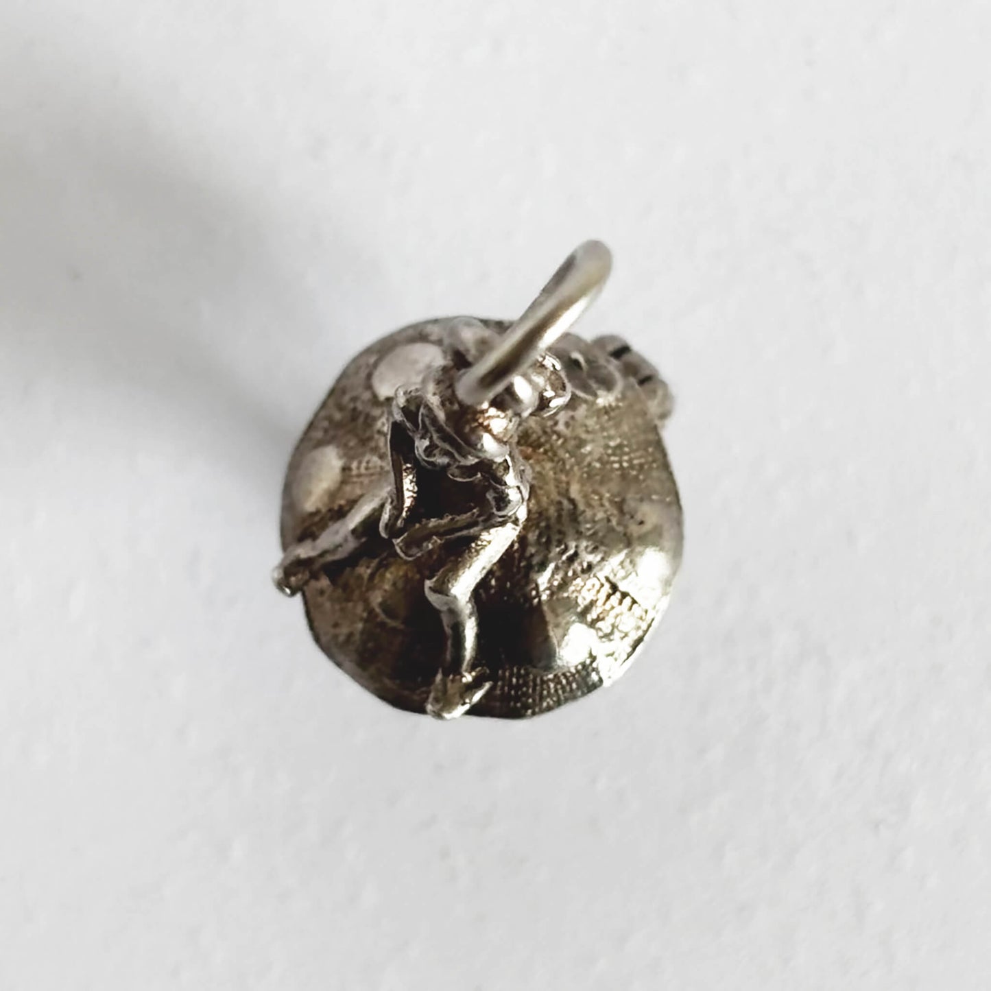 Silver leprechaun on toadstool charm seen from top on a white background