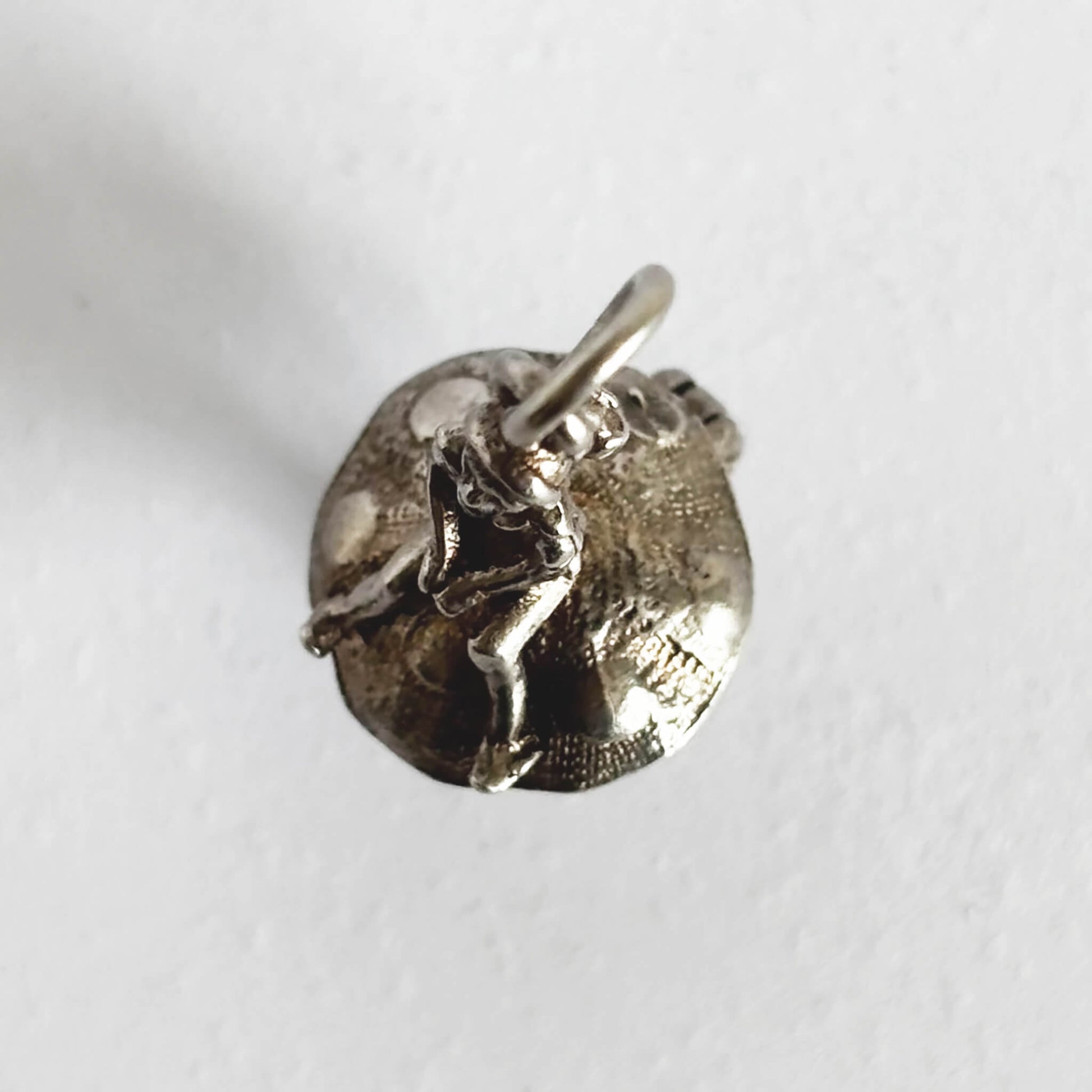 Silver leprechaun on toadstool charm seen from top on a white background