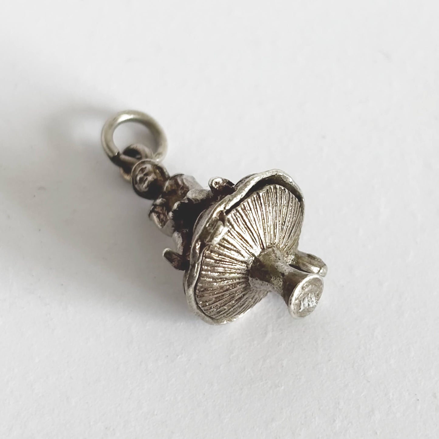 Underside of silver leprechaun on toadstool charm on a white background