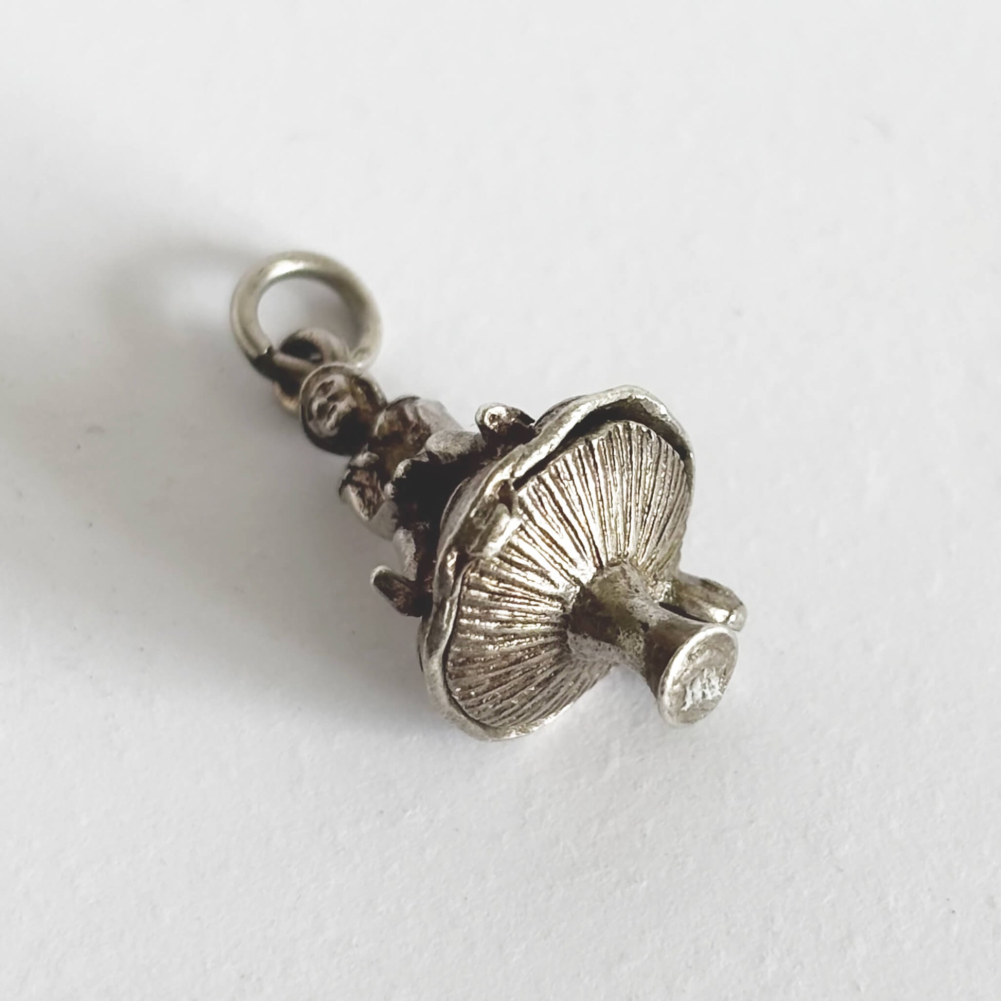 Underside of silver leprechaun on toadstool charm on a white background