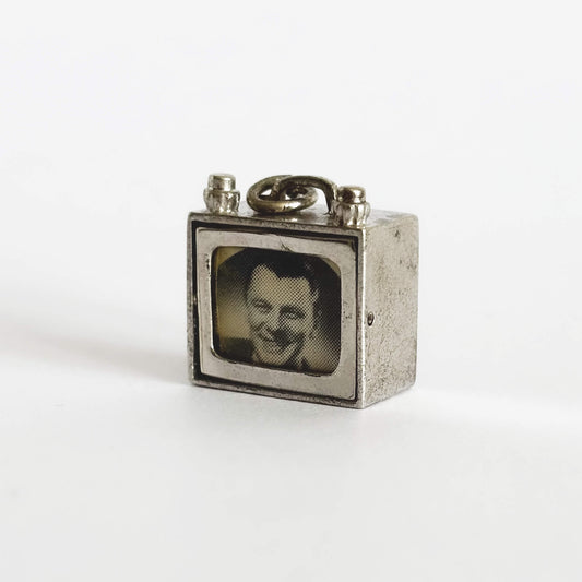 Silver pendant shaped like a vintage television set with a man's face on the screen against a white background