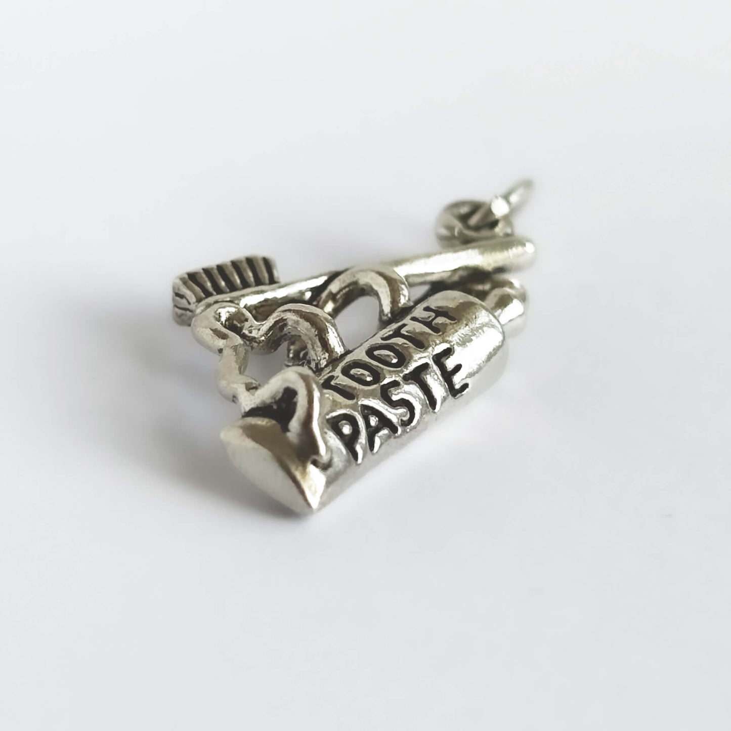 Silver toothpaste and toothbrush charm on white background
