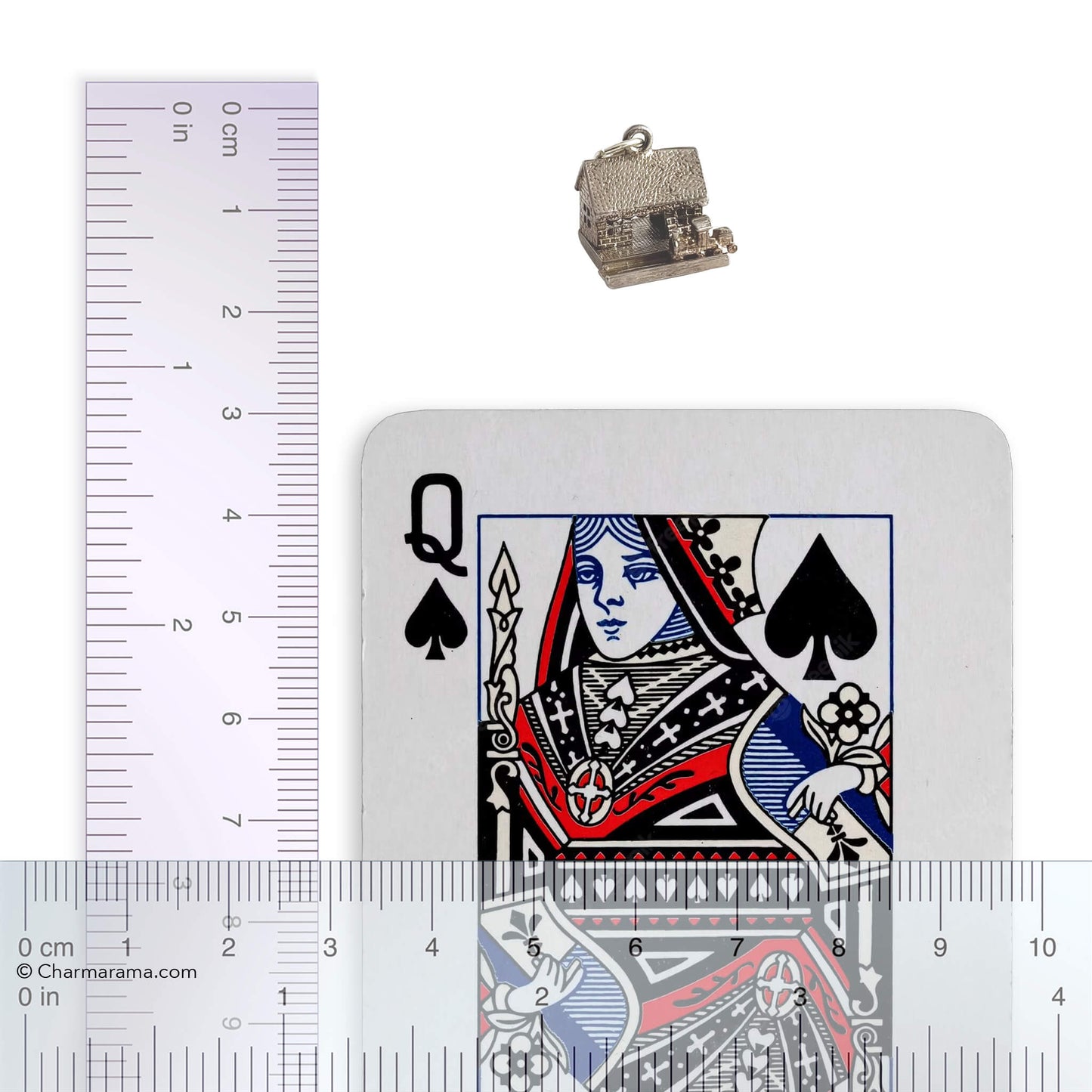 A vintage silver train in station charm on a white background with playing card and ruler for scale.
