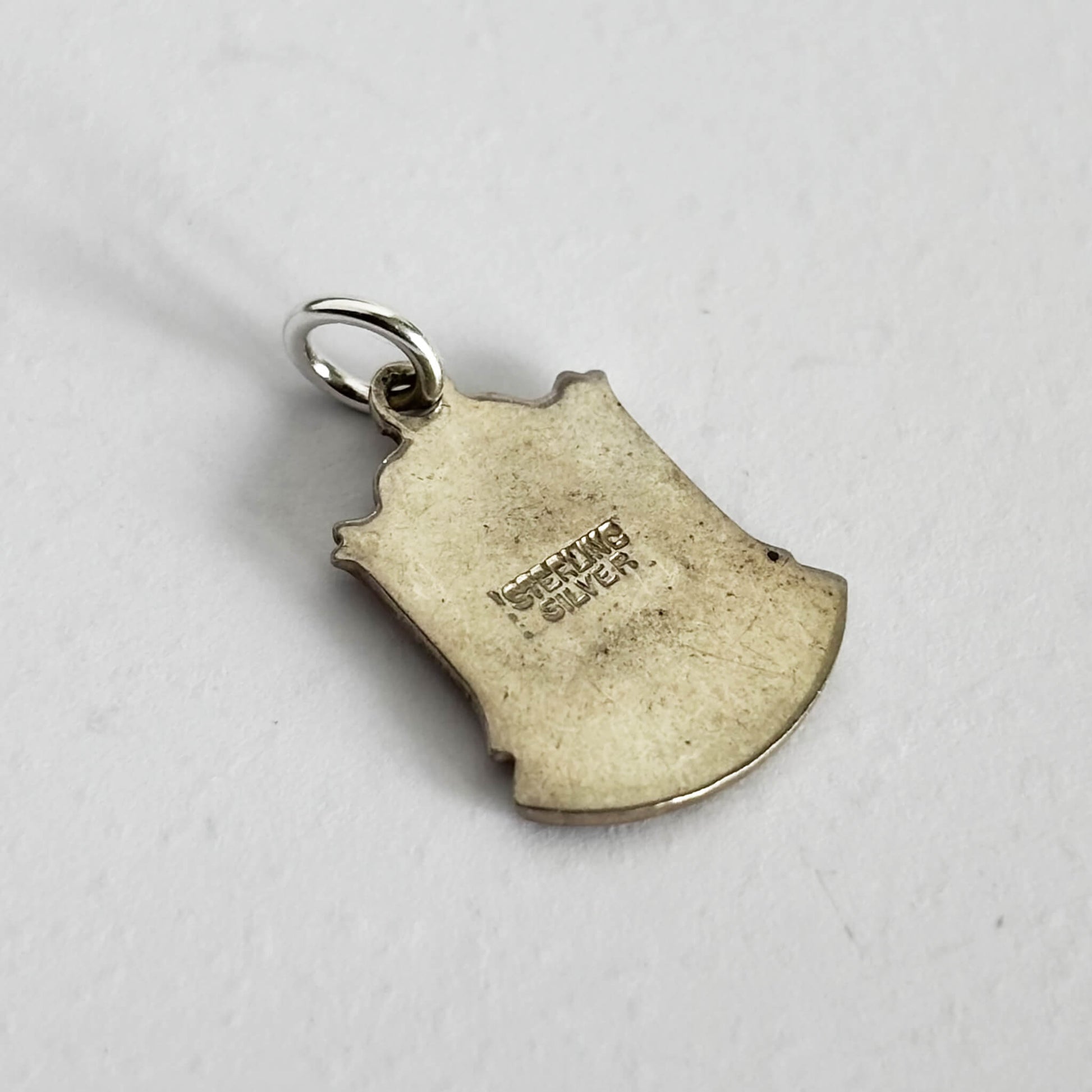 Reverse side of a sterling silver Italy flag travel shield charm on a white background