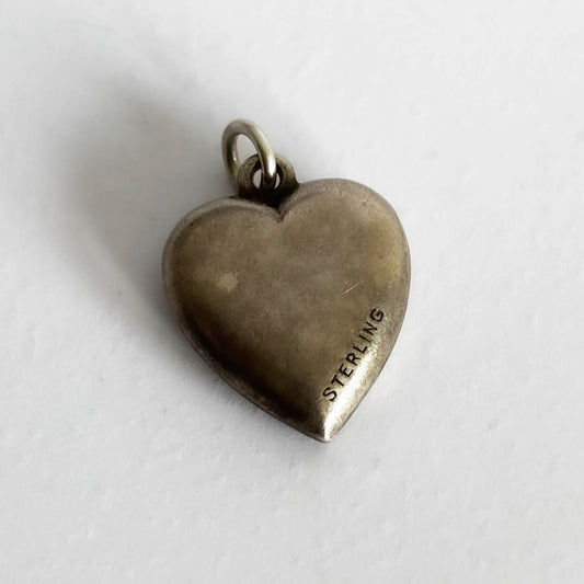 Reverse side of a sterling silver antique heart charm on a white background