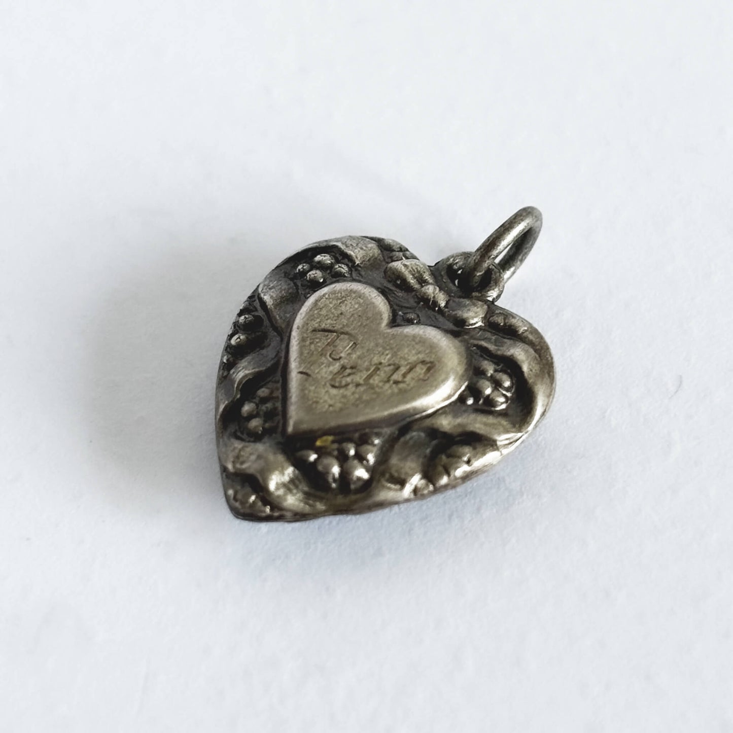 Silver heart-shaped pendant with engraved text on a white background