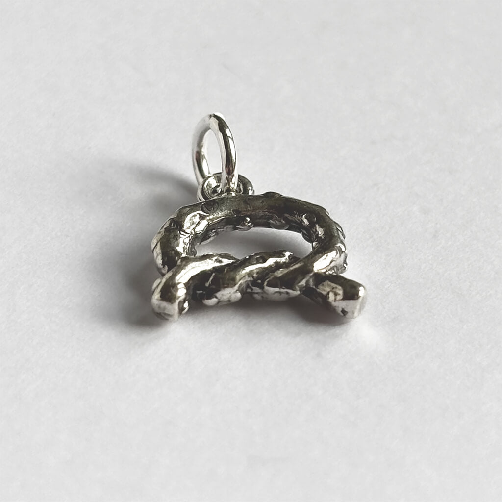 3D Sterling silver pretzel charm on light grey background