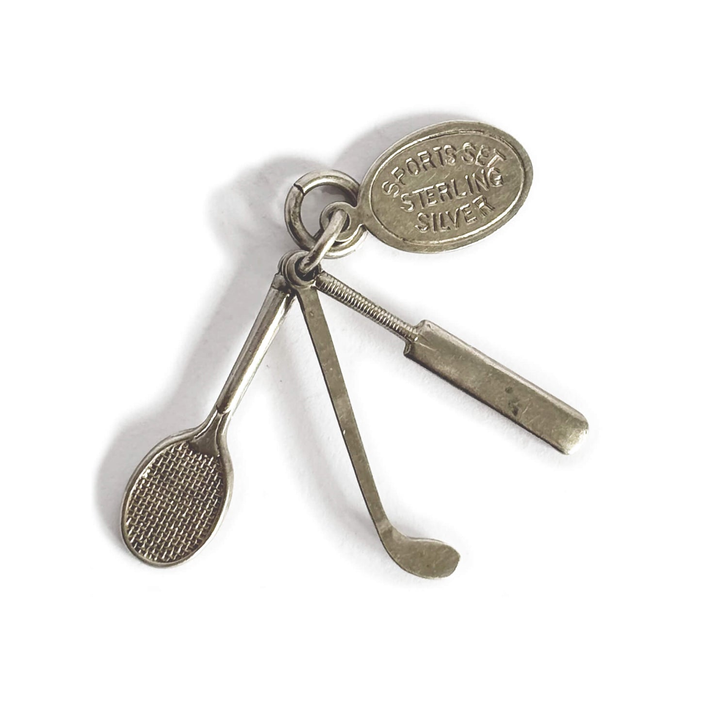 silver charm comprising a tennis racquet, golf club, cricket bat on a white background
