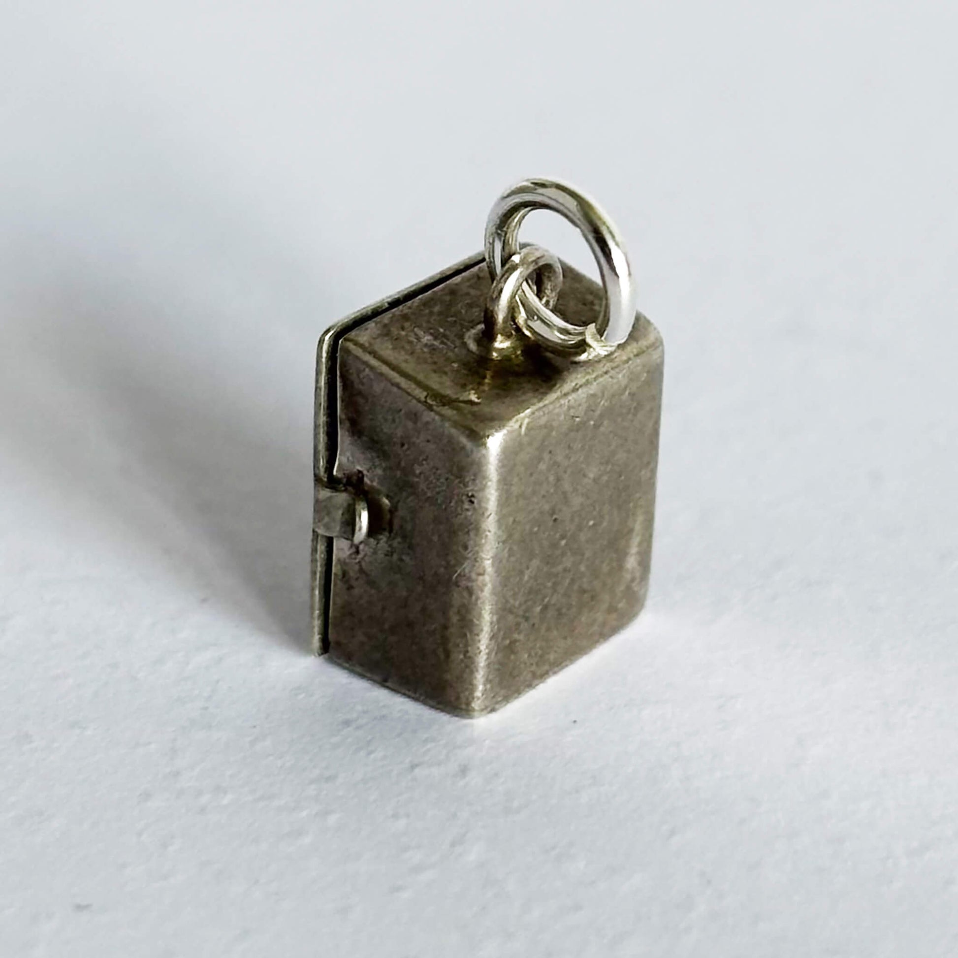 Reverse side of a sterling silver prison cell charm on a white background