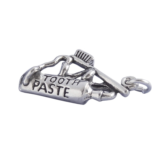 Silver toothpaste and toothbrush charm on white background