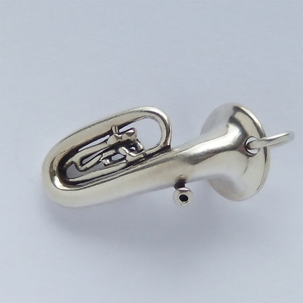 Silver tuba pendant on a light gray background