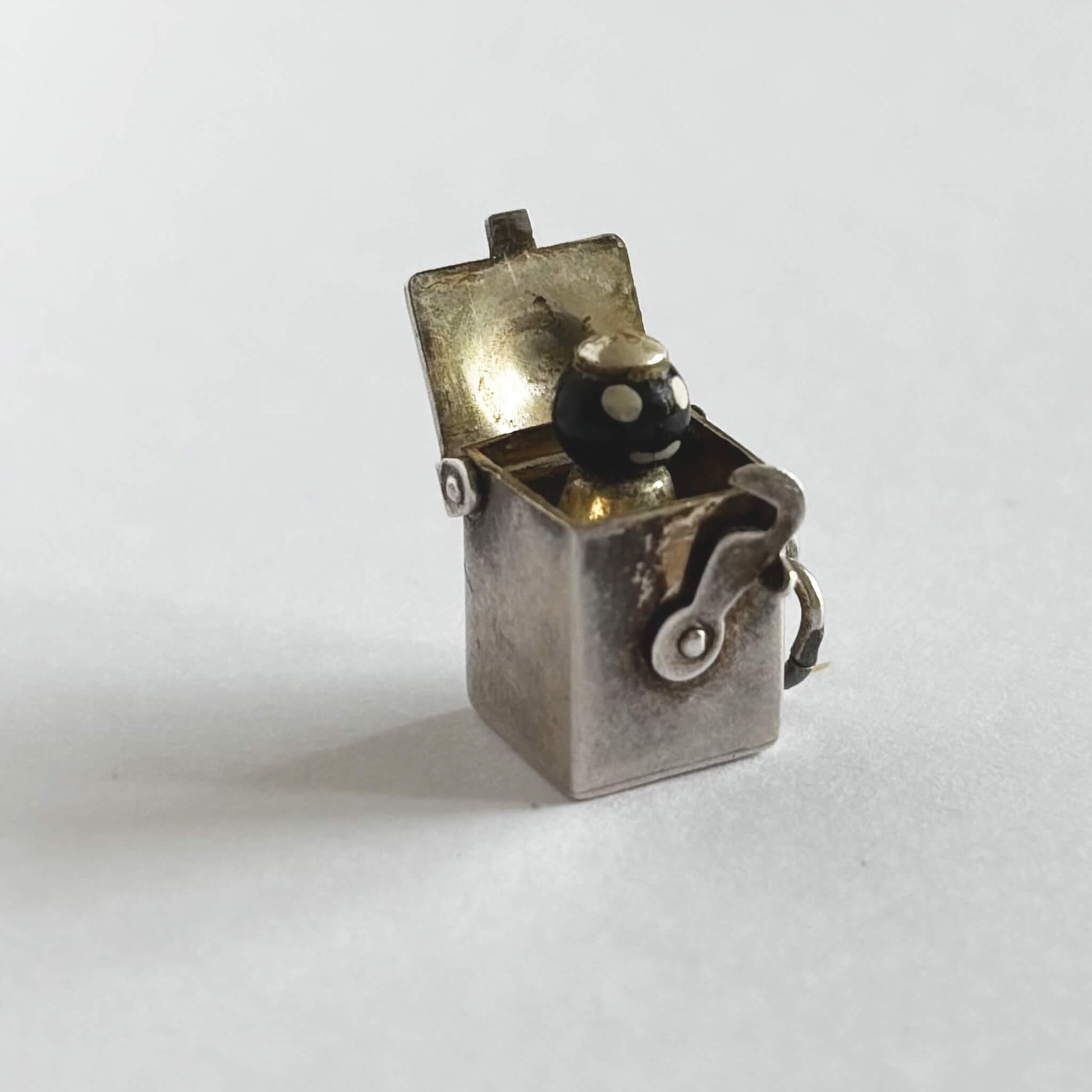 Vintage sterling silver Jack-in-the-box charm, open to reveal tiny figure, on white background