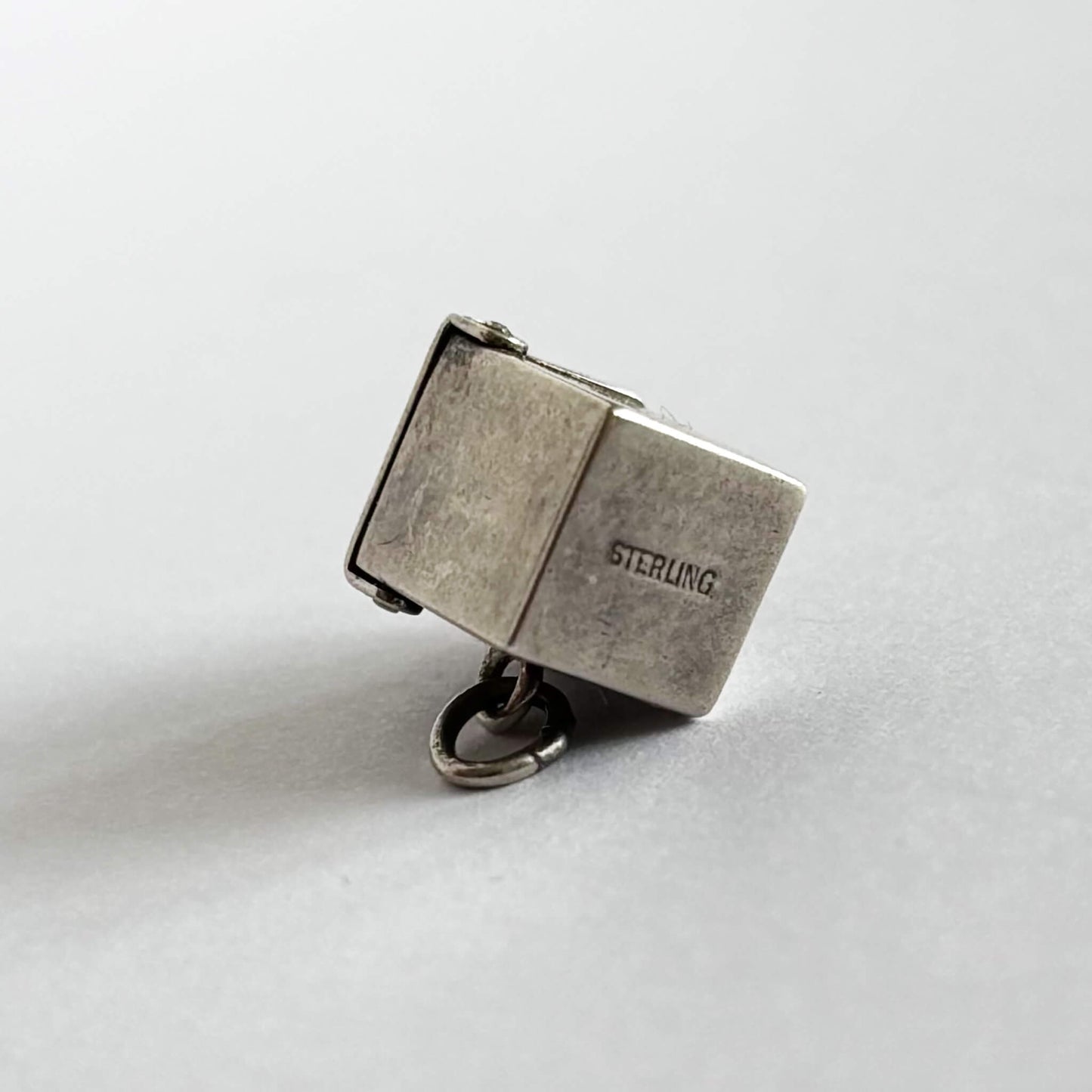 Vintage sterling silver Jack-in-the-box charm, view of bottom to show STERLING stamp, on white background