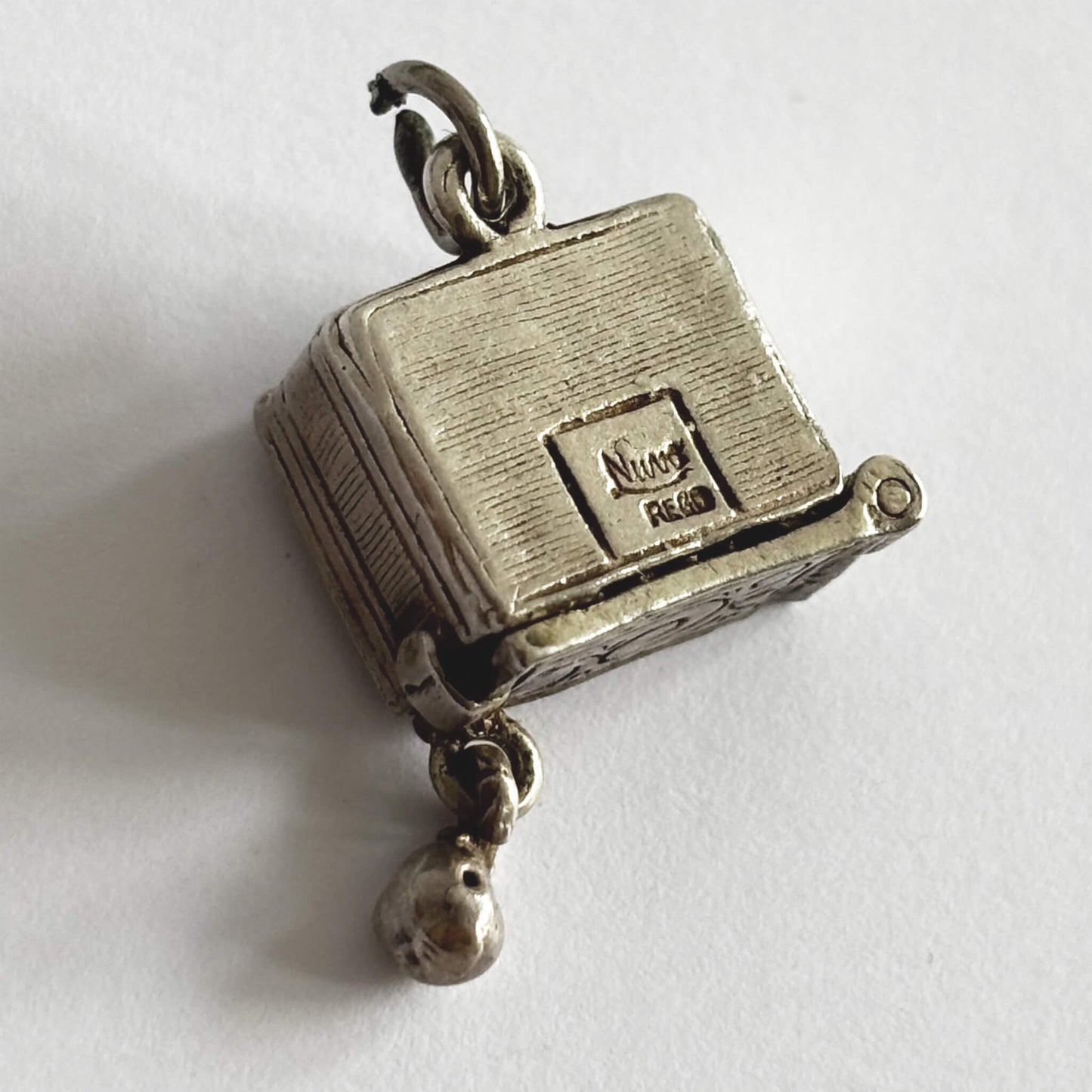 Back of a rare vintage silver bowling alley charm with ball and skittles inside, made by Nuvo, on a white background