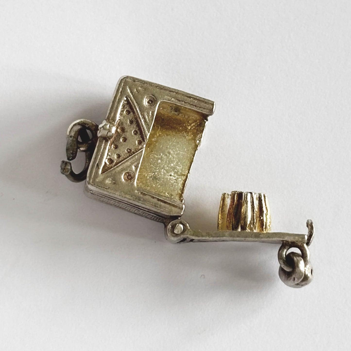 A very rare vintage silver bowling alley charm with ball and skittles inside, made by Nuvo, on a white background