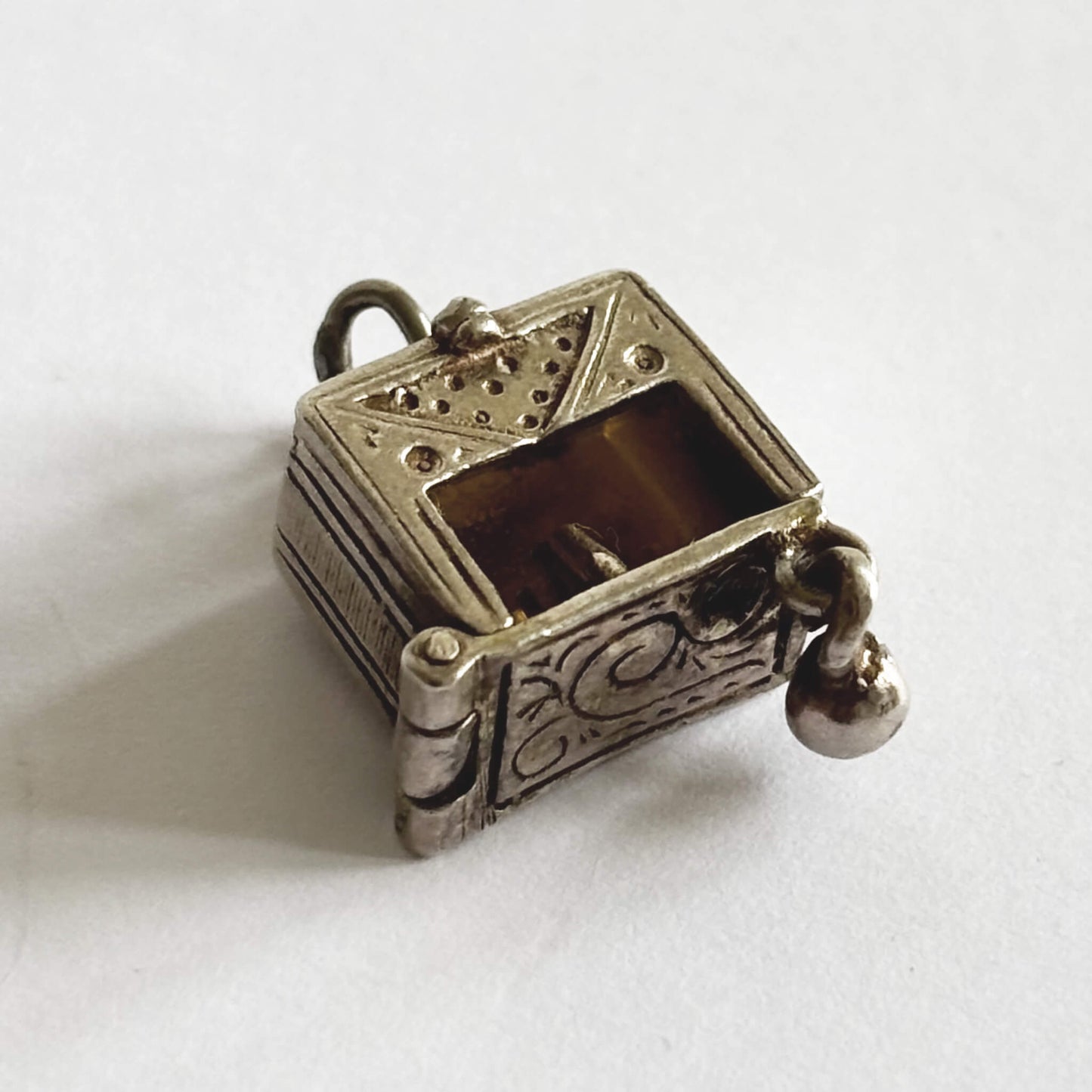 A rare vintage silver bowling alley charm with ball and skittles inside, made by Nuvo, on a white background