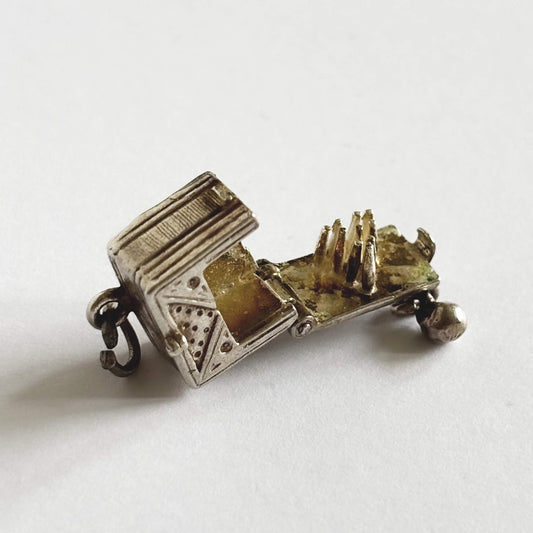 A rare vintage silver bowling alley charm with ball and skittles inside, made by Nuvo, on a white background