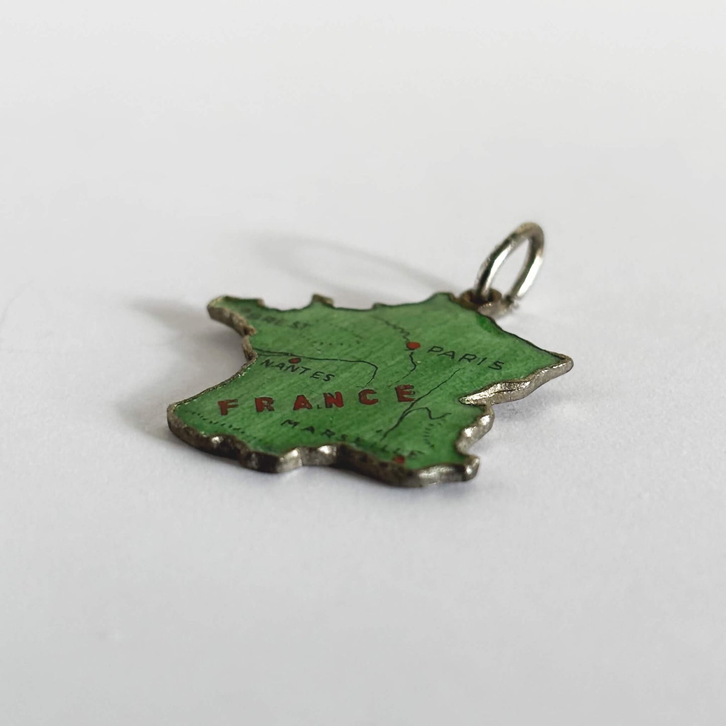 Green enamel France map charm on light grey background