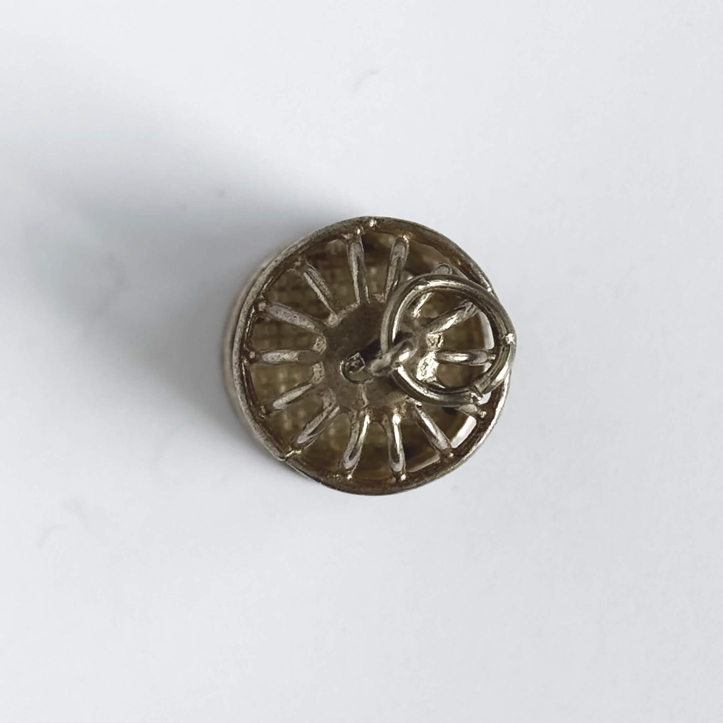 Vintage silver bird in a cage charm on a white background.