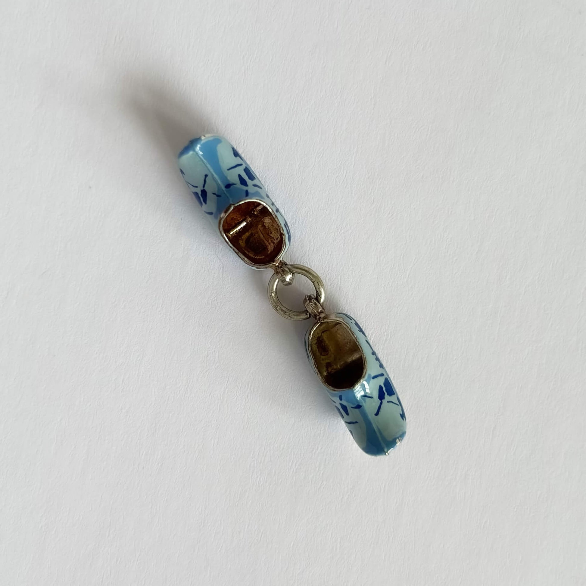 Decorative pendant resembling a shoe with blue design on a white background