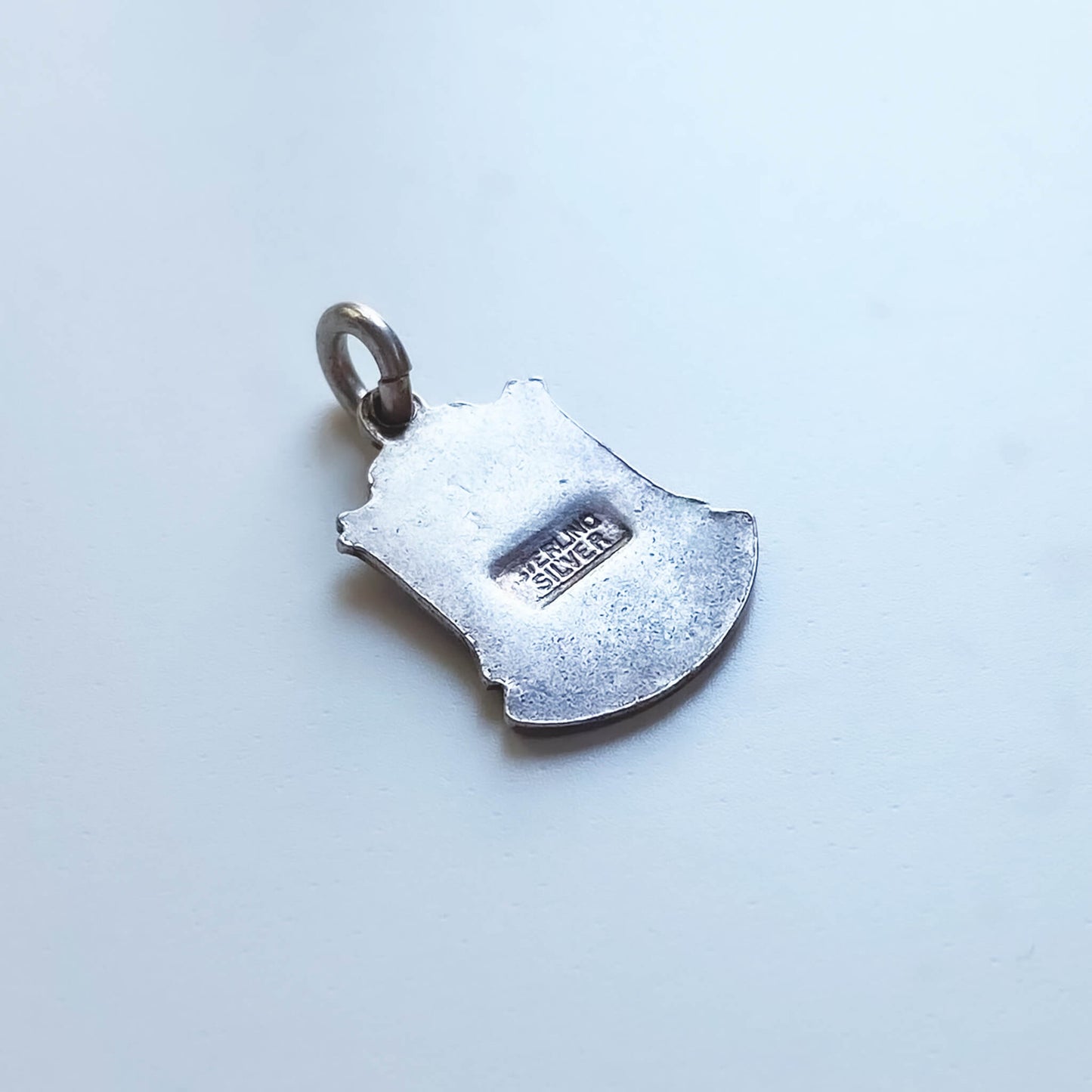 Silver shield-shaped pendant on a light gray background