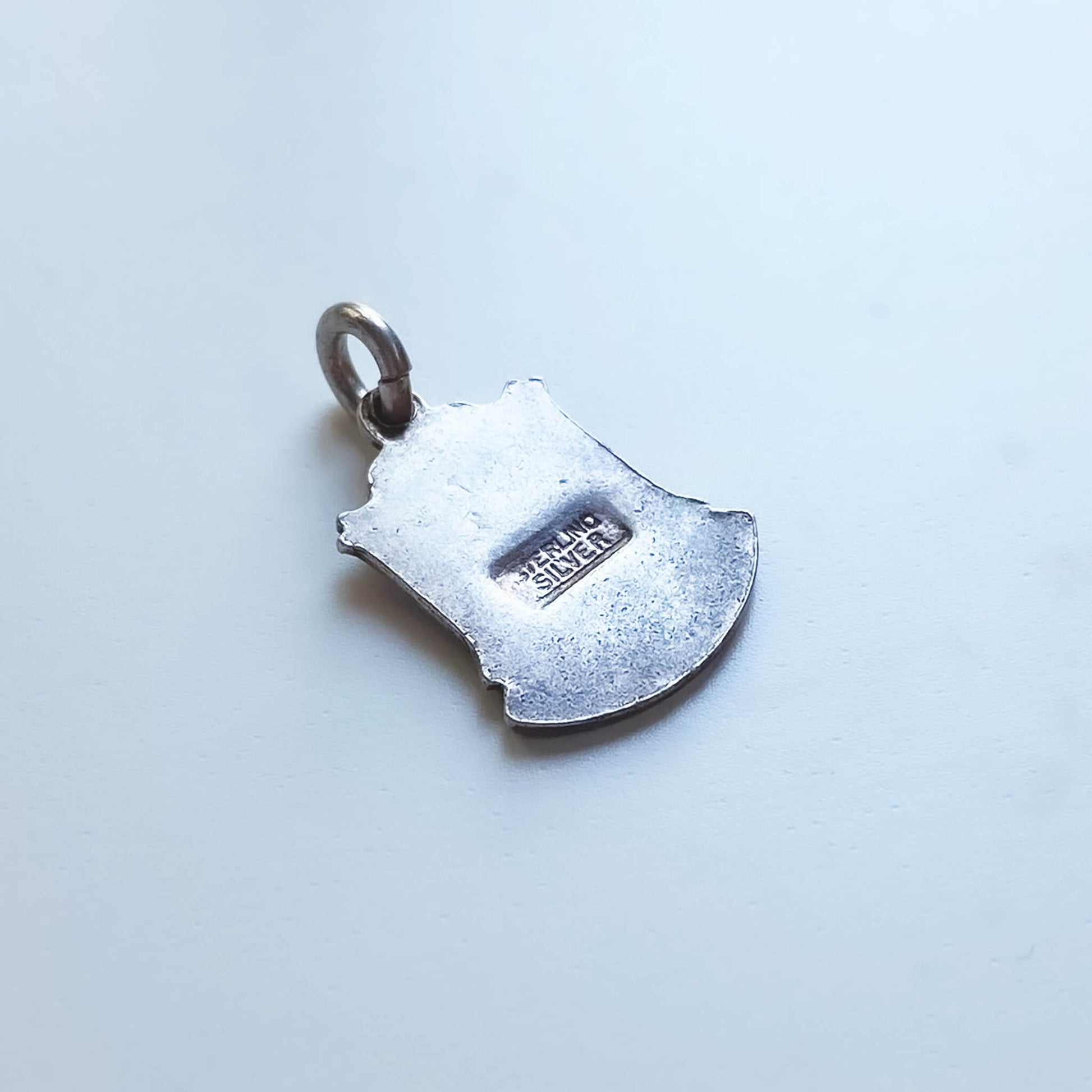 Silver shield-shaped pendant on a light gray background