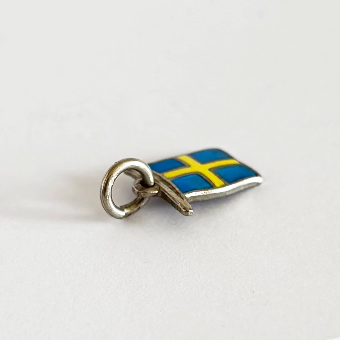 Vintage silver flag of Sweden charm with blue and yellow enamel on a white background