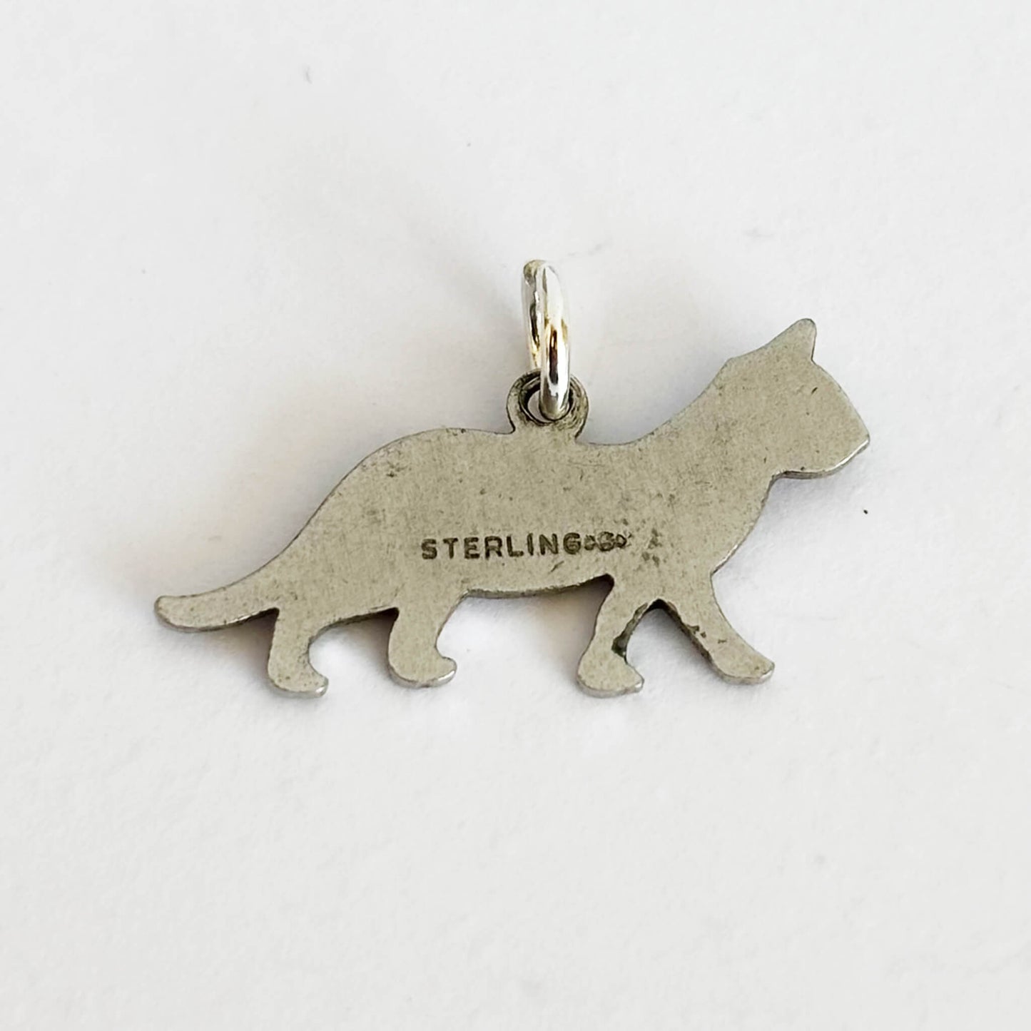 Back of a hallmarked silver cat charm on white background