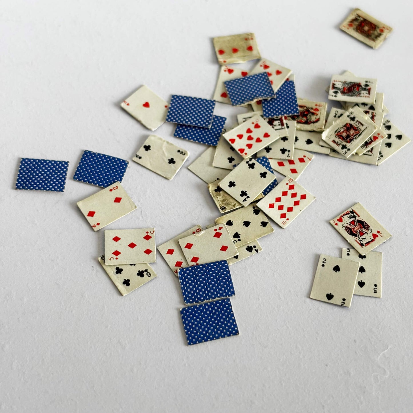Scattered miniature playing cards on a light gray surface