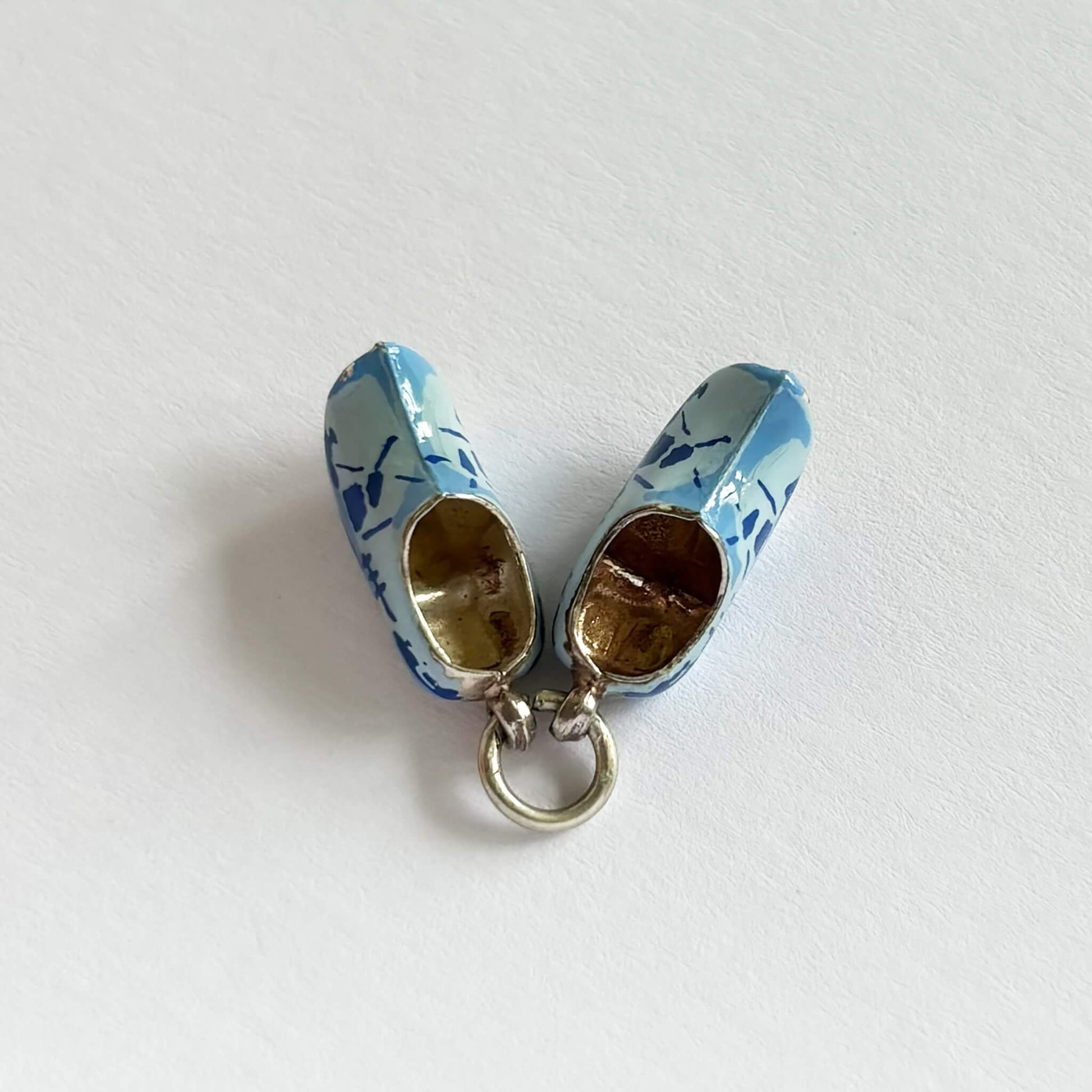 Pair of blue and white clog shoes charm on a white background