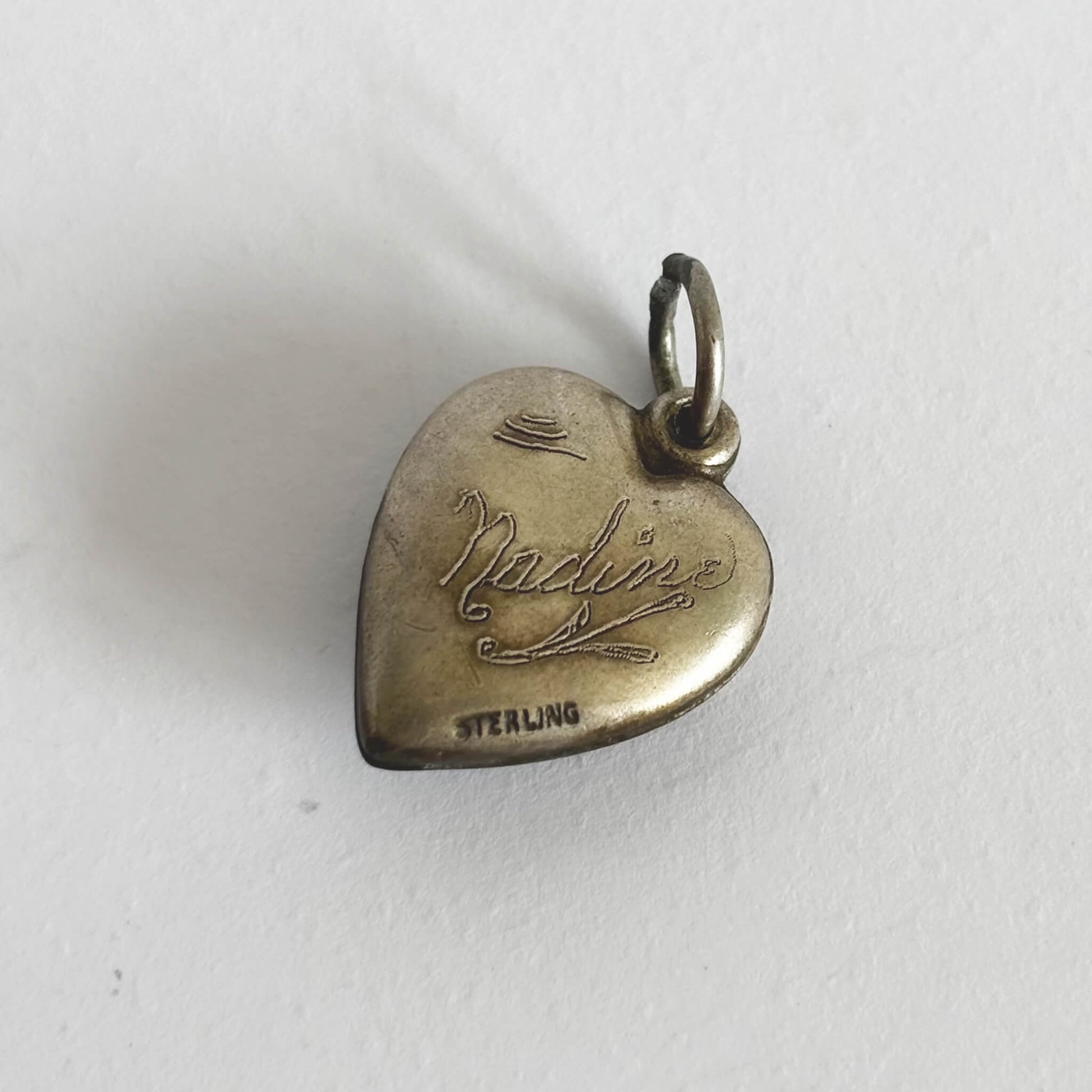 Heart-shaped sterling silver pendant with 'Nadine' engraving on a white background