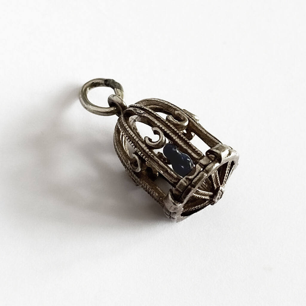Silver bird cage pendant on a white background