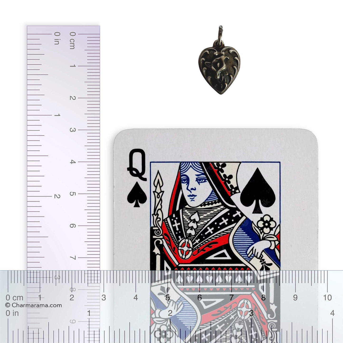 Heart-shaped pendant next to a playing card and ruler for scale