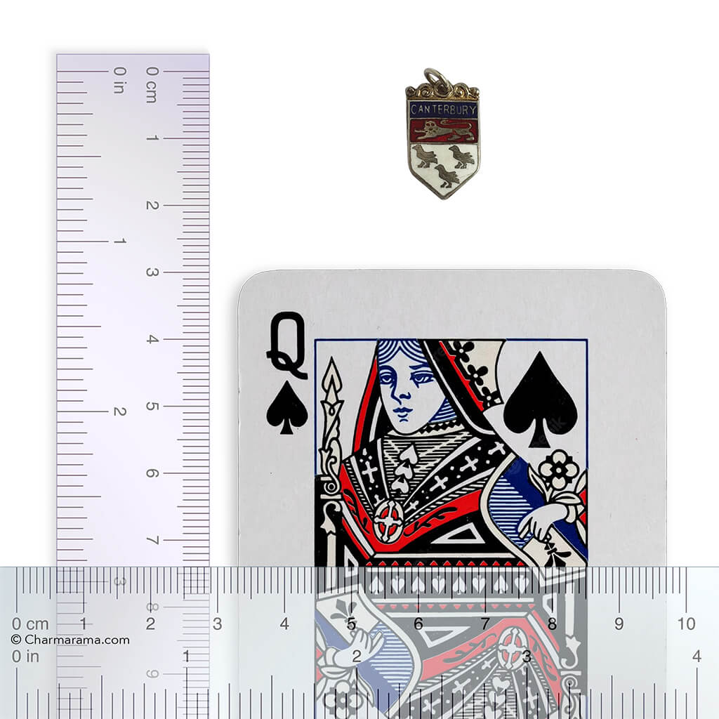 Playing card with Queen of Spades design next to a ruler and a Canterbury pendant for scale.