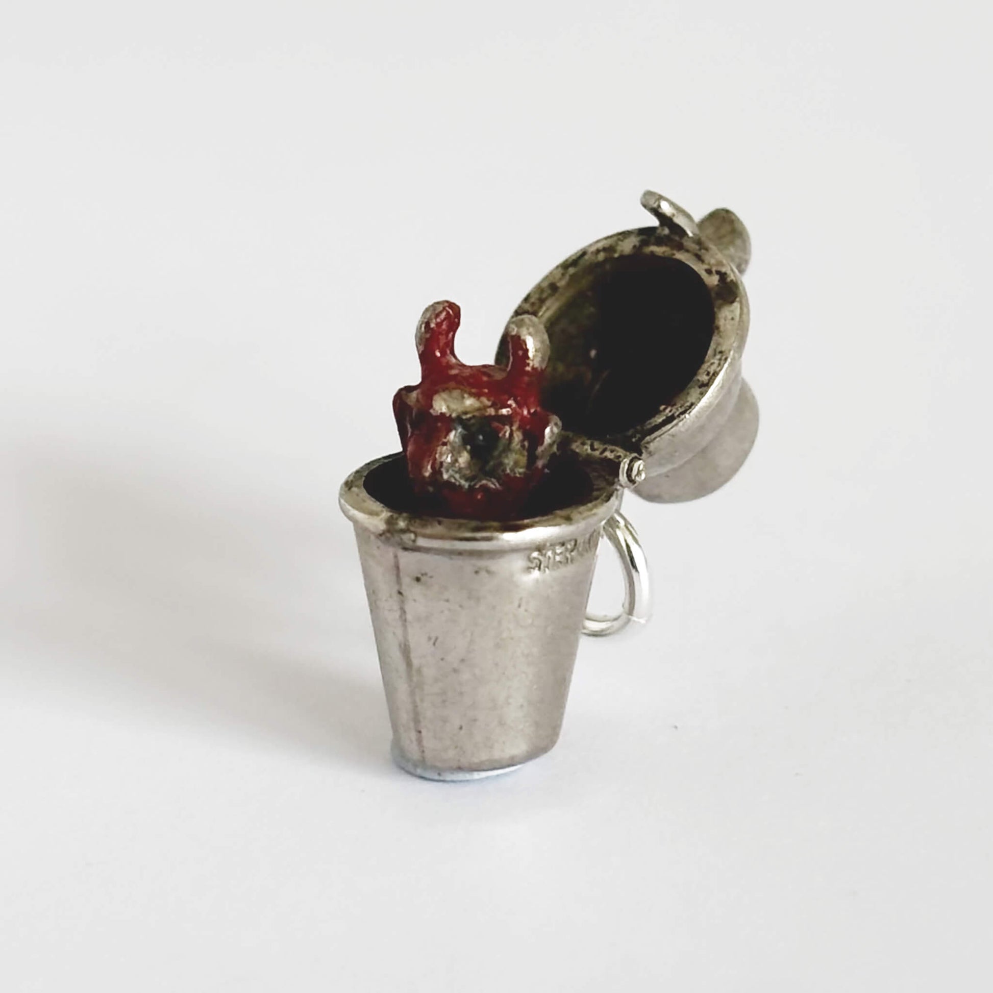 Vintage silver cocktail shaker charm opens to a red enamel devil on a white background