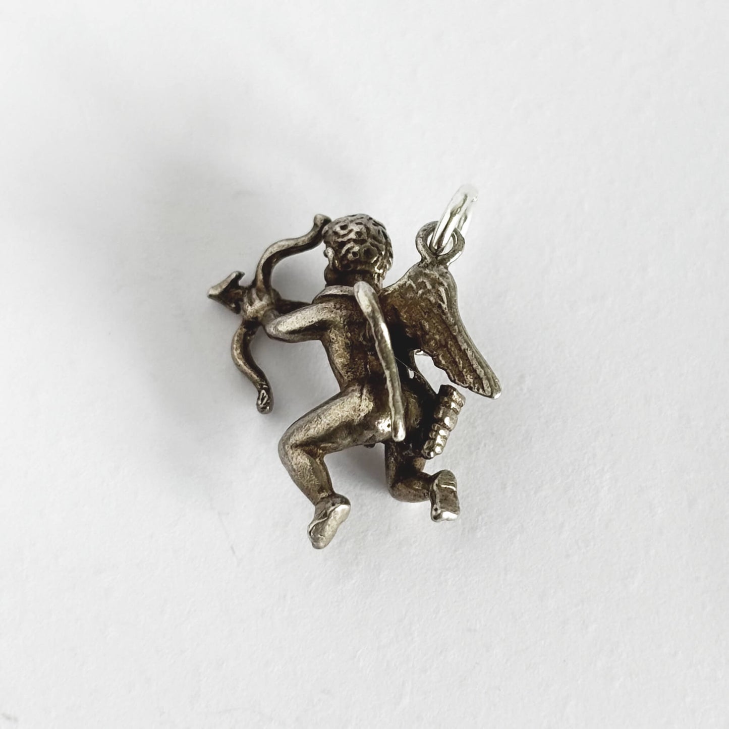 Silver cherub with bow and arrow charm on a white background