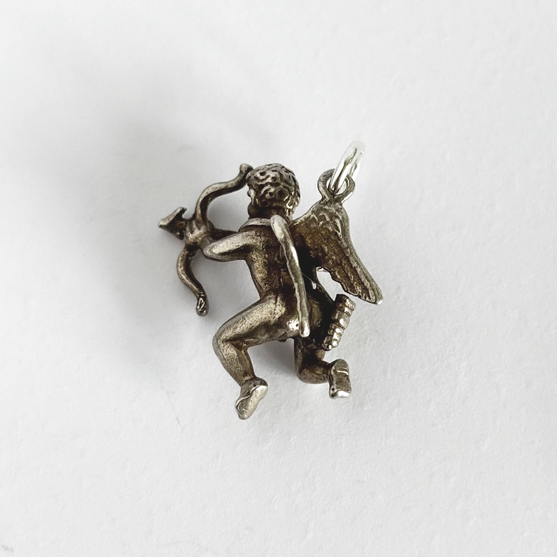 Silver cherub with bow and arrow charm on a white background