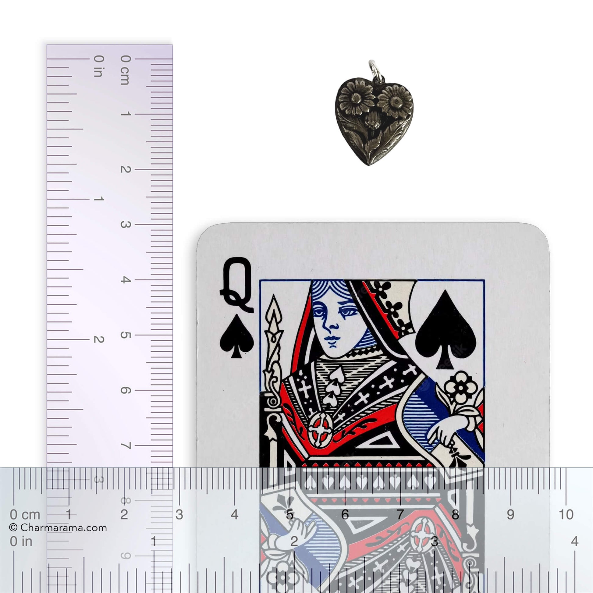 Heart-shaped pendant with a playing card and a ruler for scale on a white background