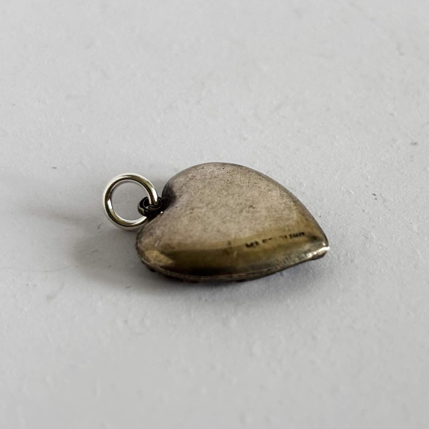 Heart-shaped silver pendant on a light gray background