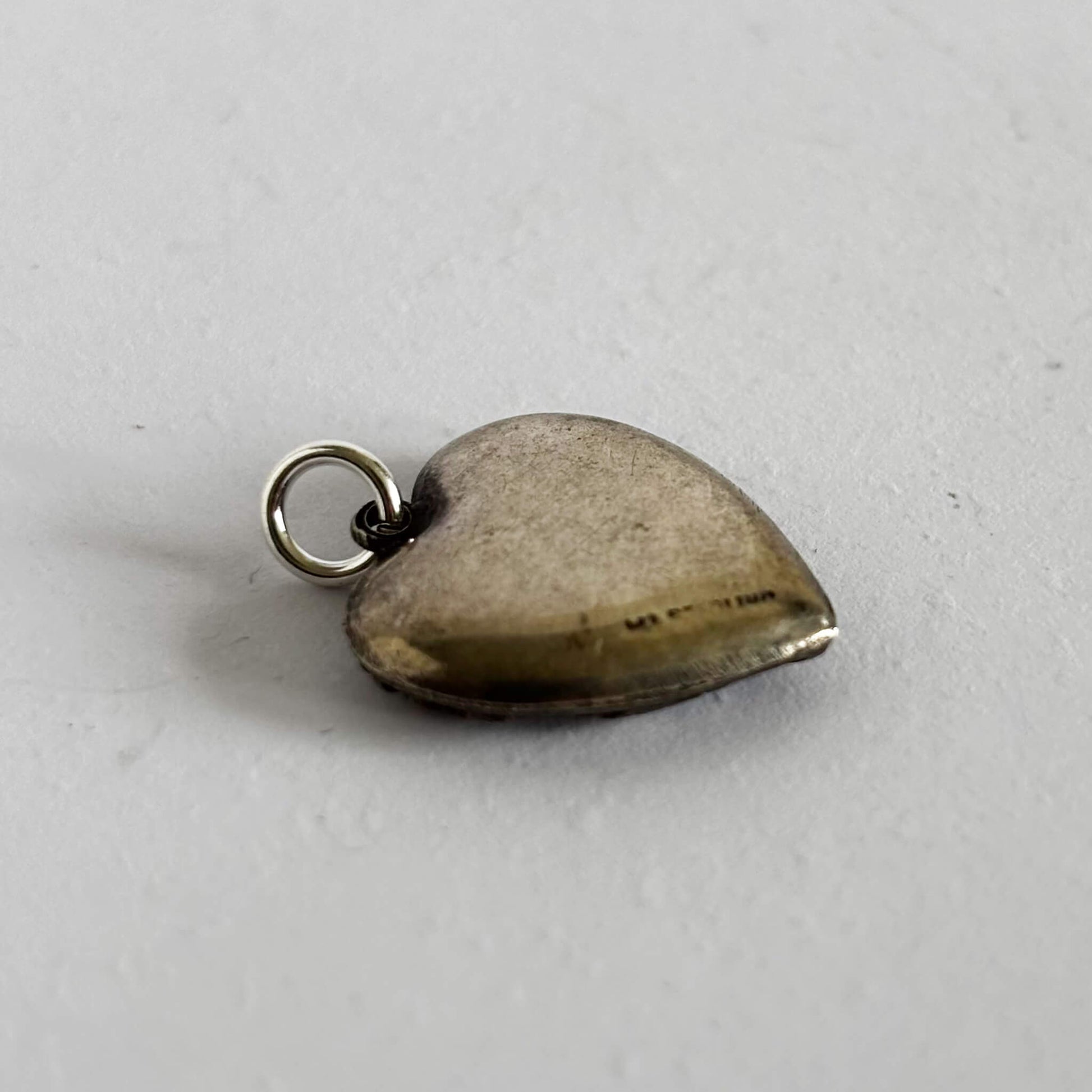 Heart-shaped silver pendant on a light gray background