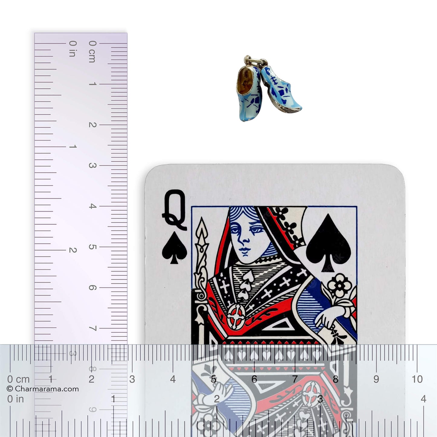 Pair of clogs charm next to a playing card with a ruler for scale