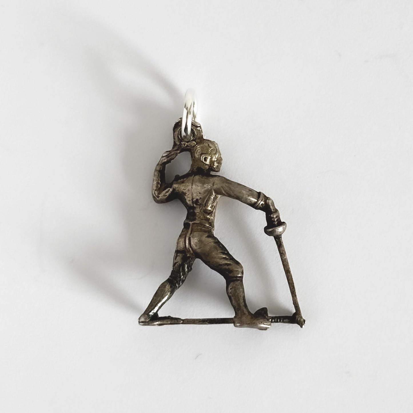 Silver pendant of a person fencing holding a sword on a white background