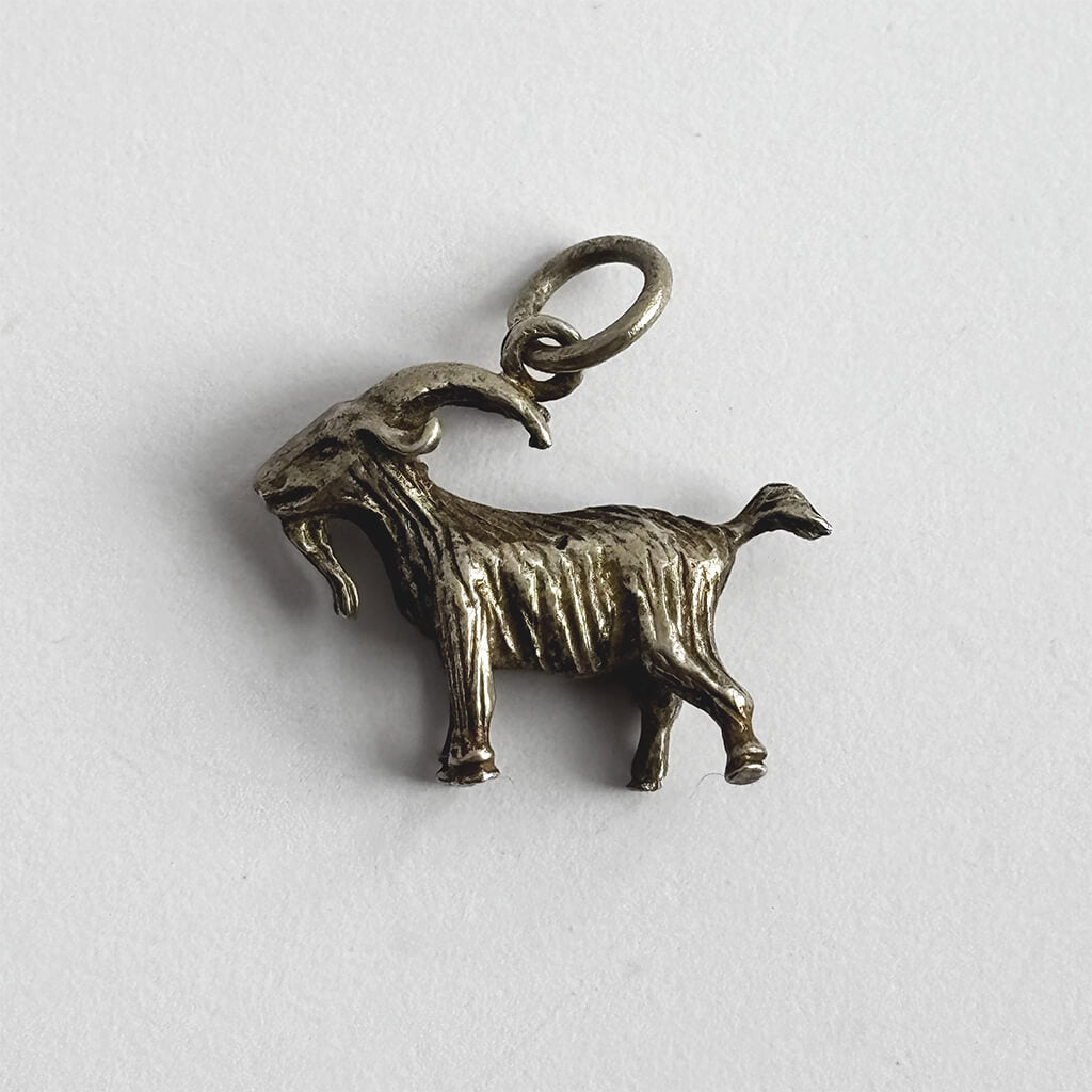 Silver goat charm on a white background